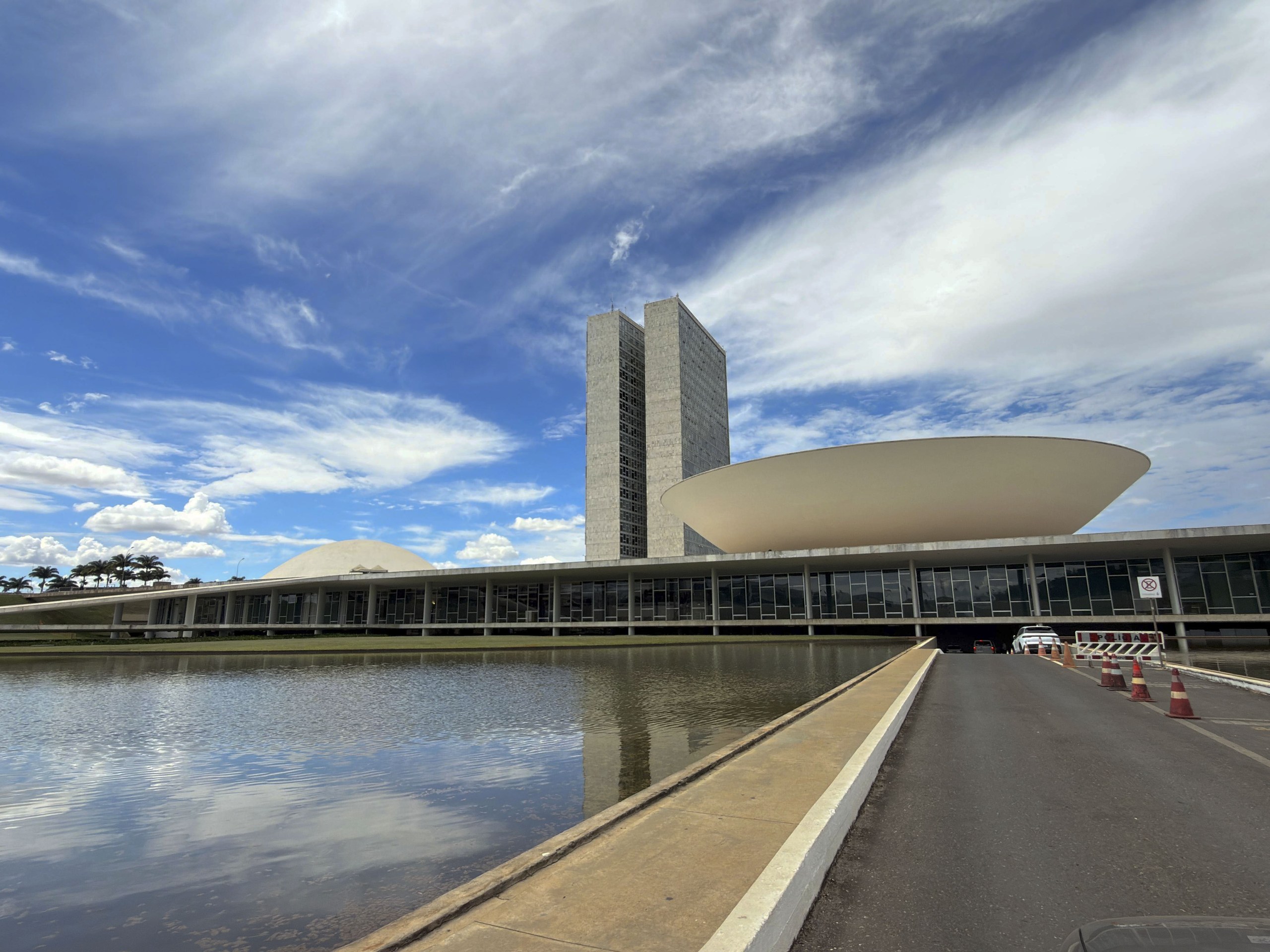 Vista externa do Congresso Nacional em Brasília, com destaque para a arquitetura de Oscar Niemeyer e o espelho d'água.