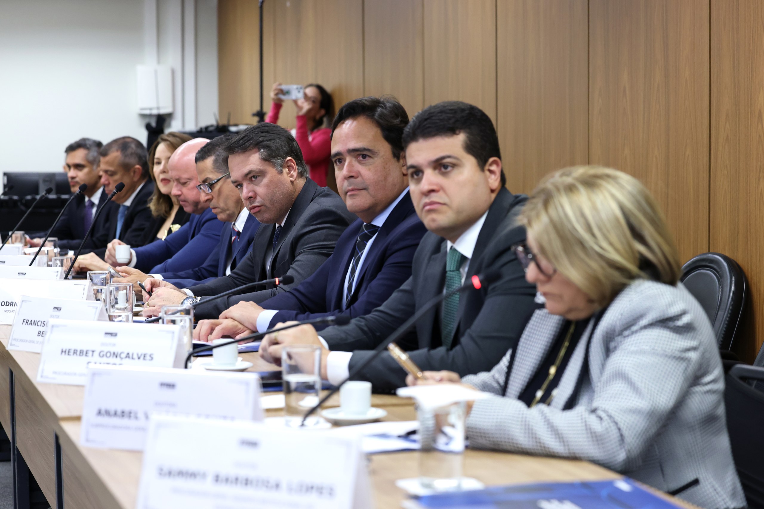Grupo de autoridades em traje formal sentadas à mesa durante uma reunião governamental.
