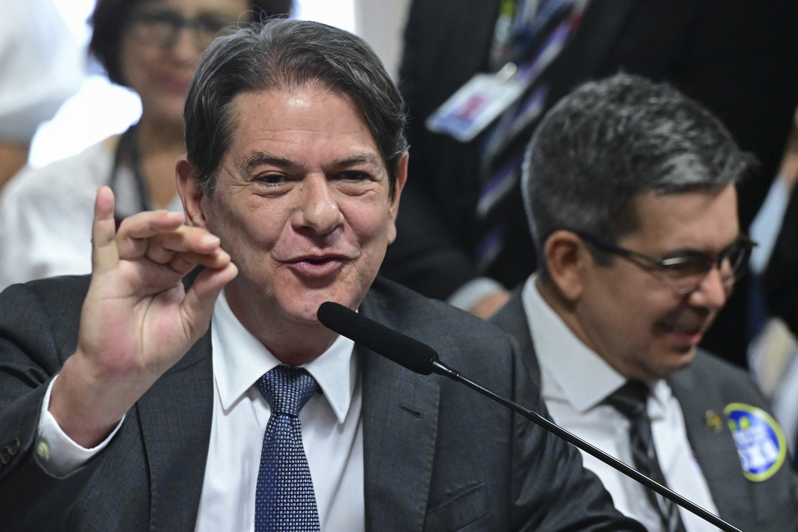 Um homem de terno e gravata fala ao microfone e gesticula com a mão direita em ambiente formal. Na foto: Cid Gomes e Randolfe Rodrigues.