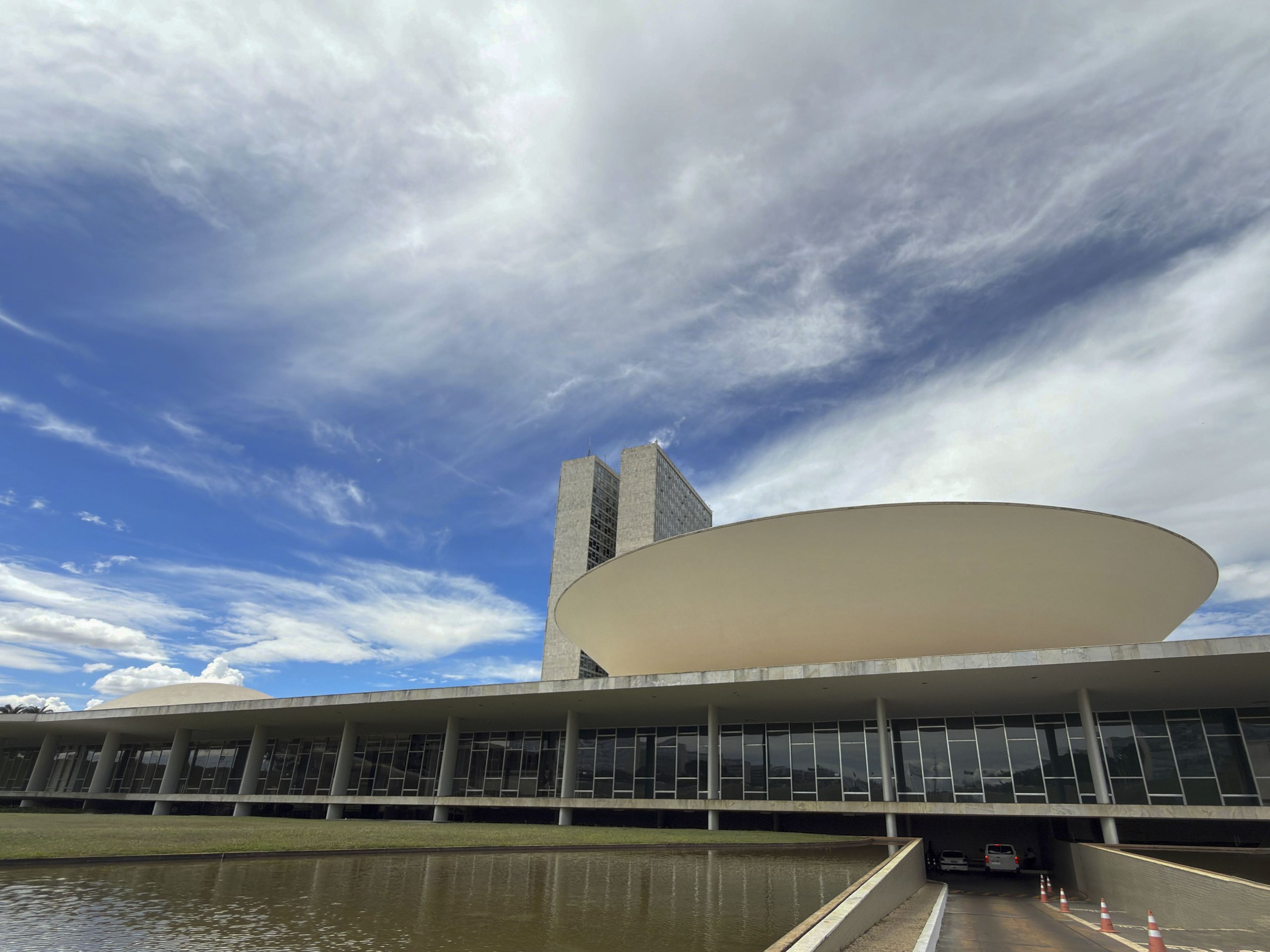 Vista externa do Congresso Nacional em Brasília sob um céu parcialmente nublado.