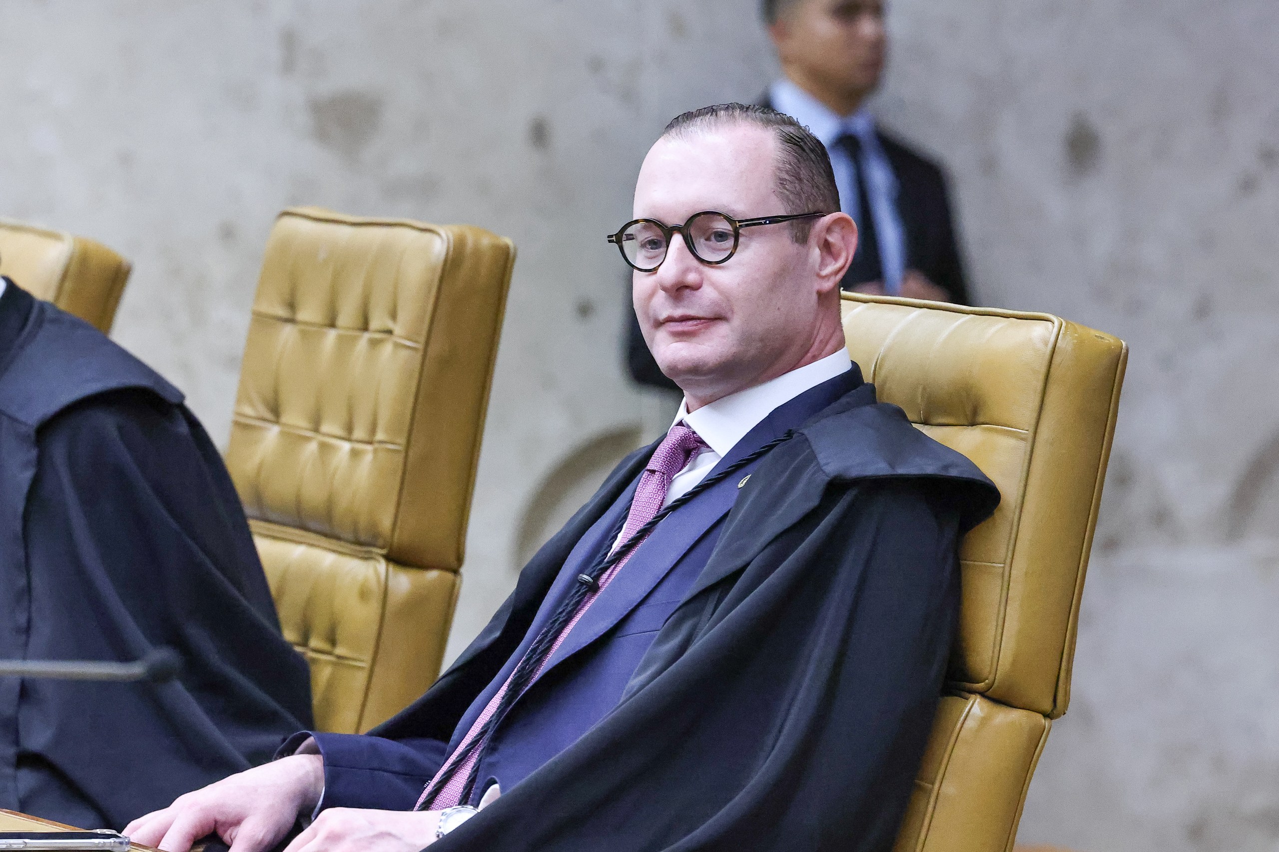 Homem trajando toga judicial sentado em cadeira de couro em ambiente formal. Na foto: Cristiano Zanin.