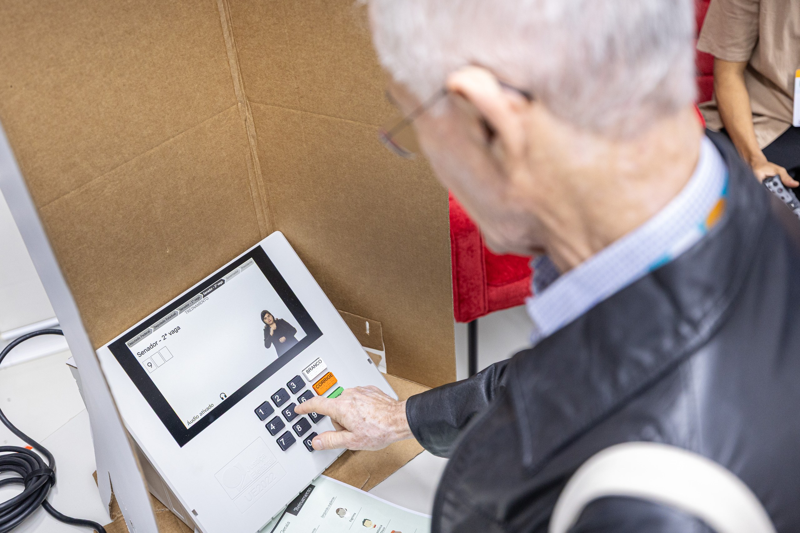 Um homem idoso votando em uma urna eletrônica durante um processo eleitoral.
