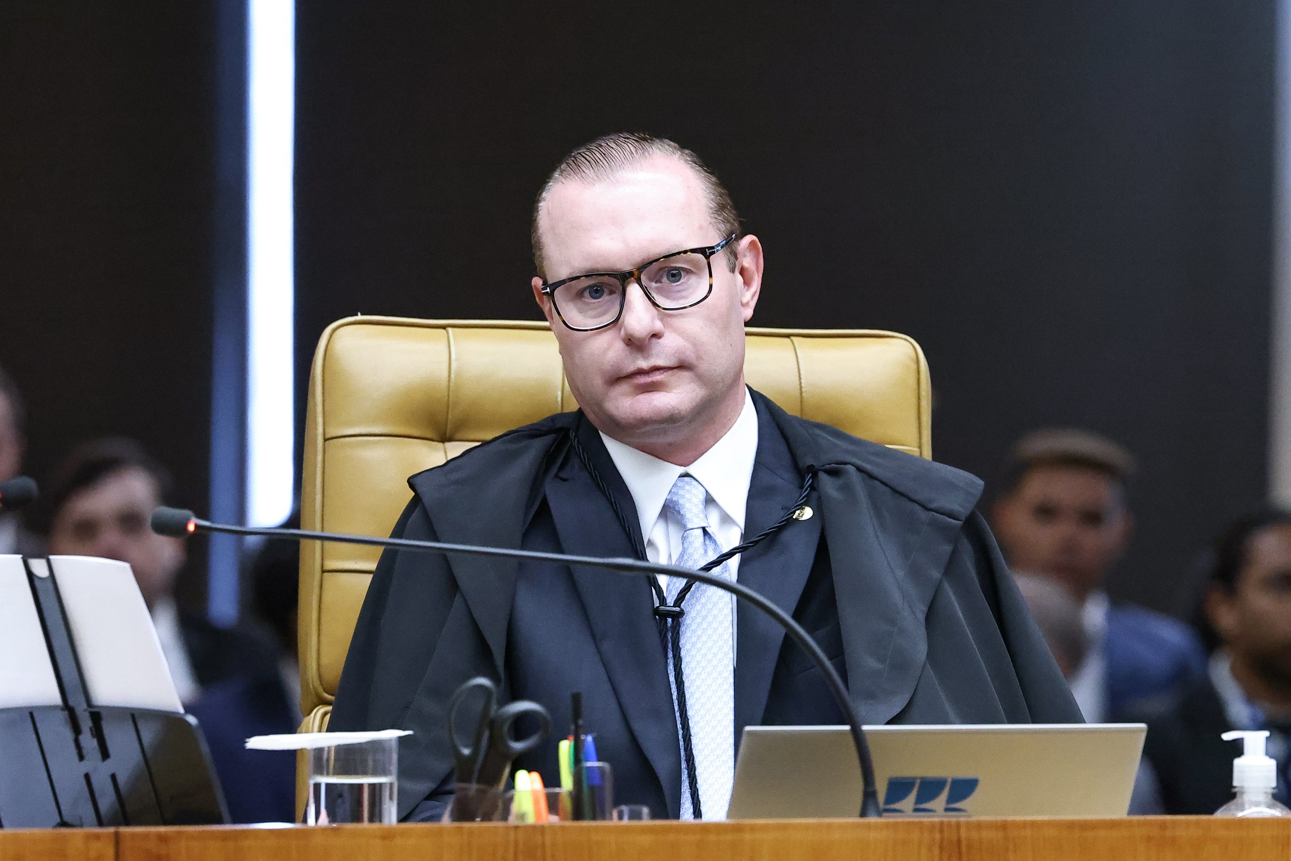 Um juiz usando toga e óculos senta-se em sua bancada durante uma sessão em um tribunal. Na foto: Cristiano Zanin.