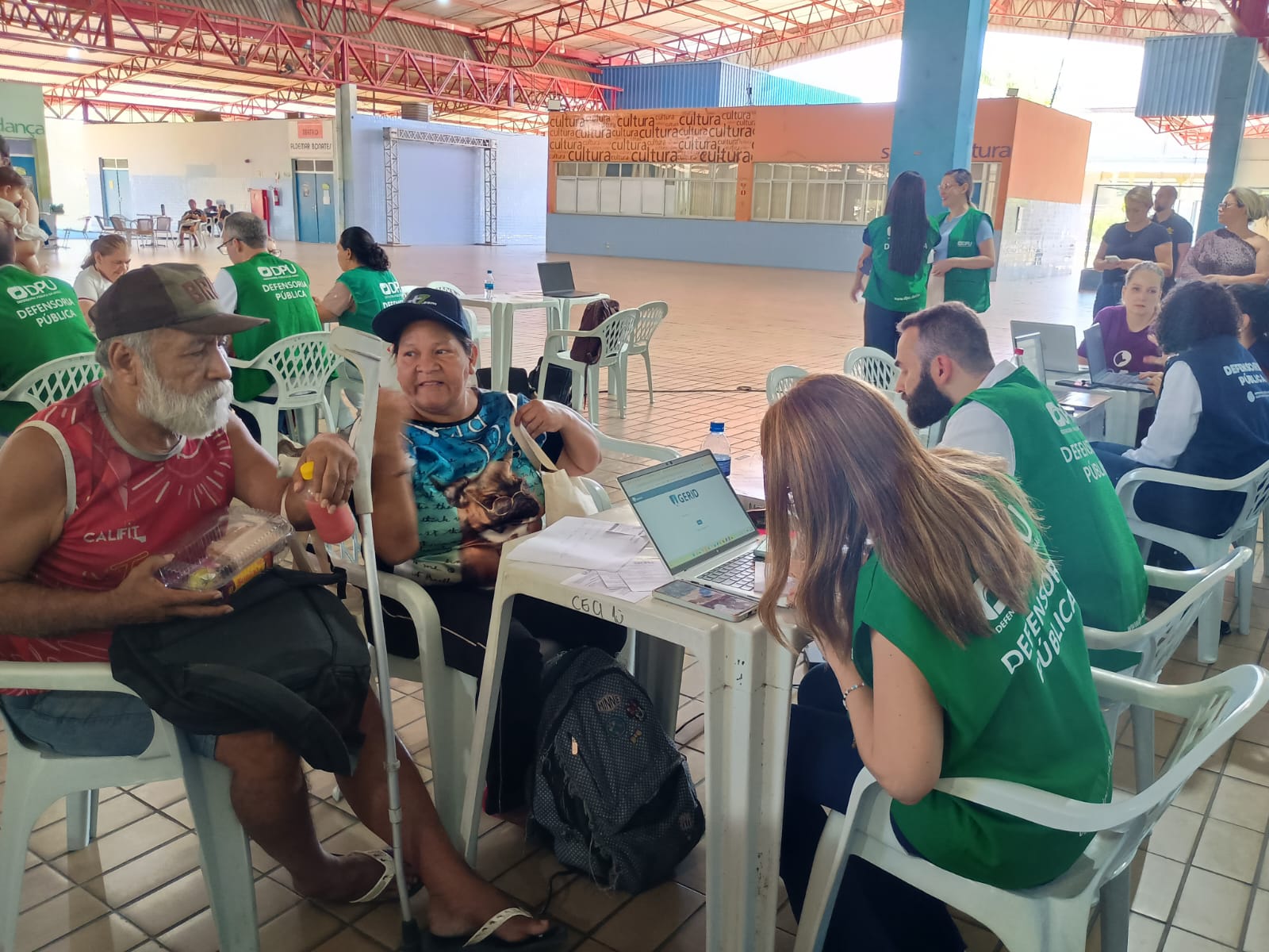 Equipe da Defensoria Pública realiza atendimento a cidadãos em um espaço aberto coberto.