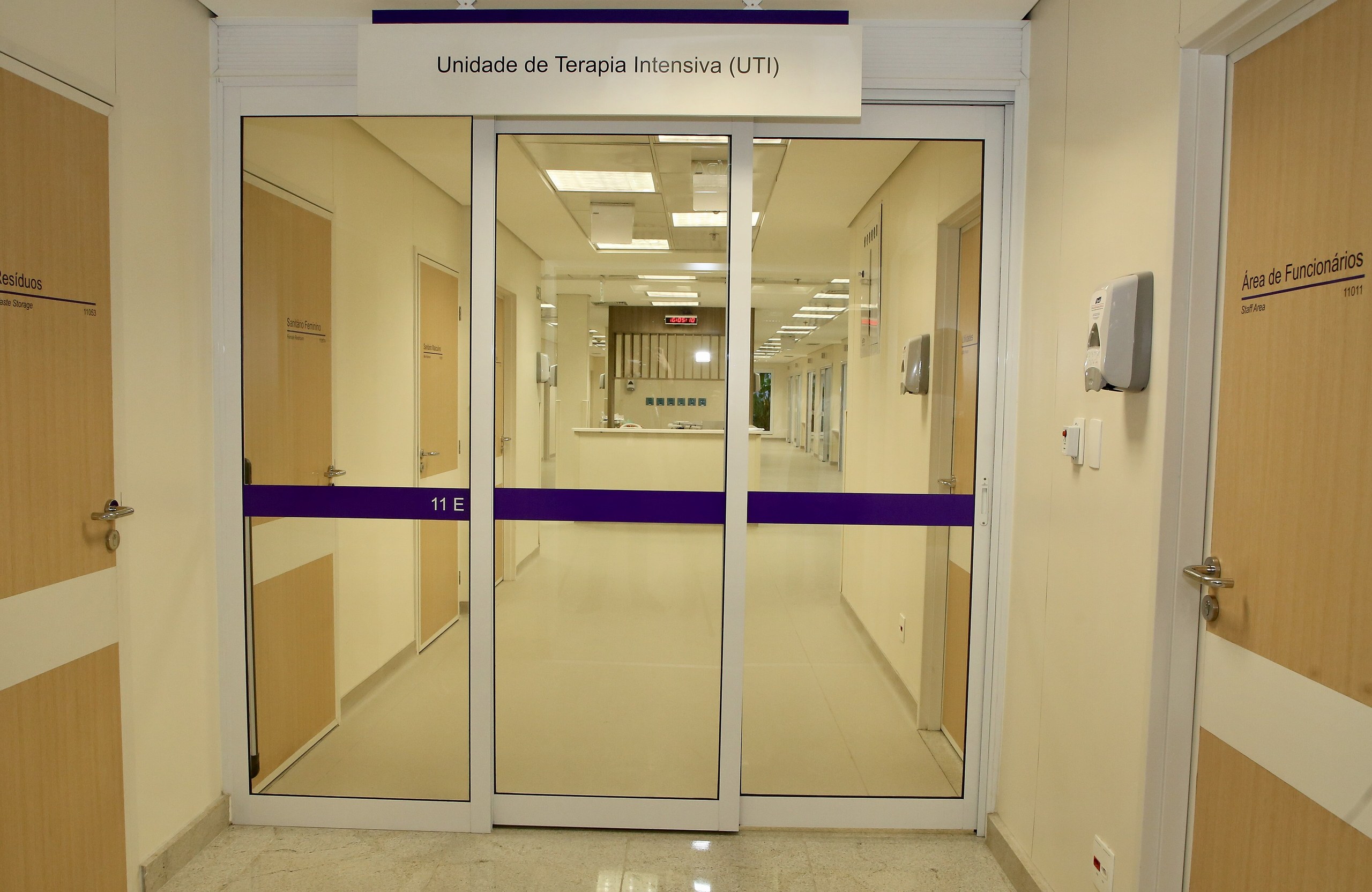 Porta de vidro com a inscrição Unidade de Terapia Intensiva (UTI) dá acesso a um corredor iluminado de um hospital.