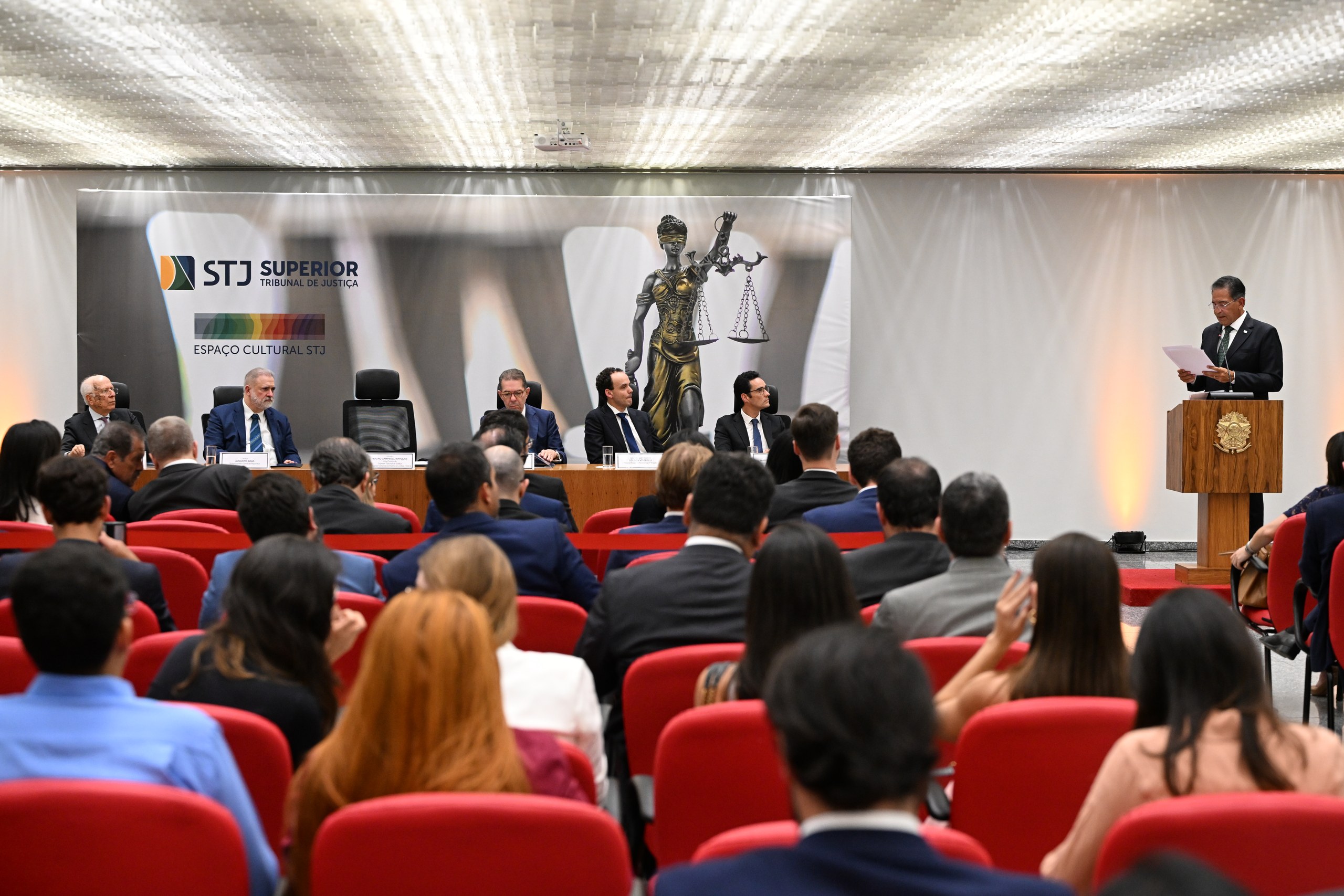 Um homem discursa em um púlpito diante de autoridades sentadas à mesa e de um público em um auditório do Superior Tribunal de Justiça.