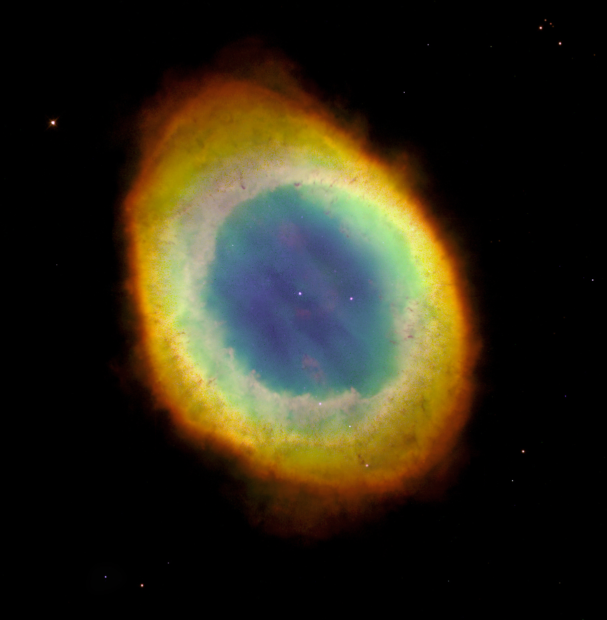 Uma nebulosa planetária em formato oval com cores vibrantes em tons de amarelo, verde e azul contra o fundo preto do espaço sideral.